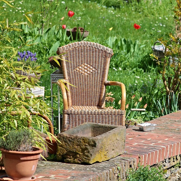 un fauteuil en rotin dans un jardin fleuri