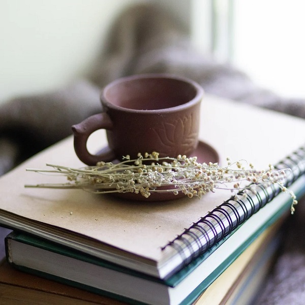 carnets avec une tasse de thé et des fleurs blanches