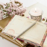 carnets à écrire avec une bougie et des fleurs roses
